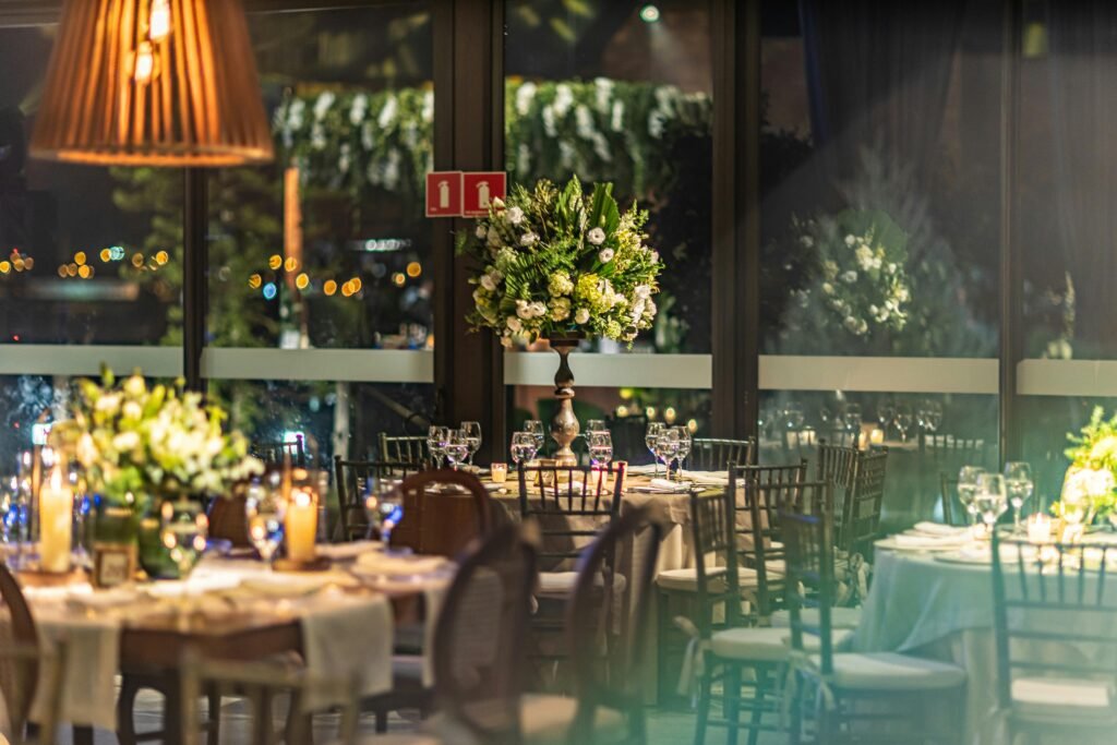 A beautifully decorated indoor banquet hall with elegant flower arrangements and ambient lighting.